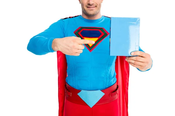 Tiro recortado de super-homem sorridente apontando com o dedo para a caixa em branco com detergente isolado em branco — Fotografia de Stock