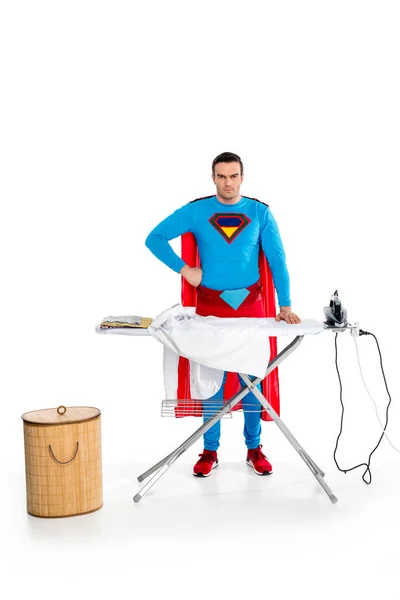 Handsome superman ironing clothes and looking at camera on white — Stock Photo