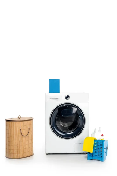 Caixa em branco com detergente na máquina de lavar roupa, material de limpeza e cesta de roupa isolada em branco — Fotografia de Stock