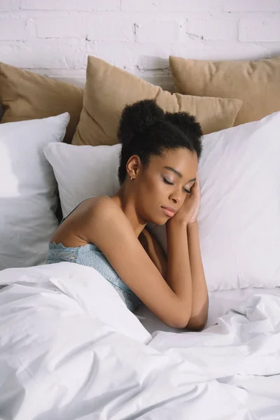 Attractive african american girl sleeping on pillows in bed — Stock Photo