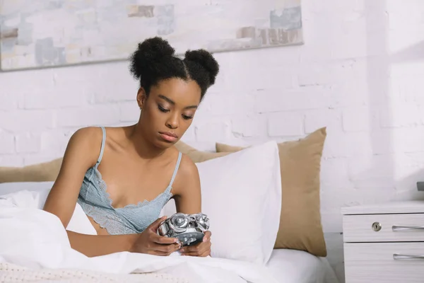 Beautiful african american girl turning off alarm clock in bed in the morning — Stock Photo