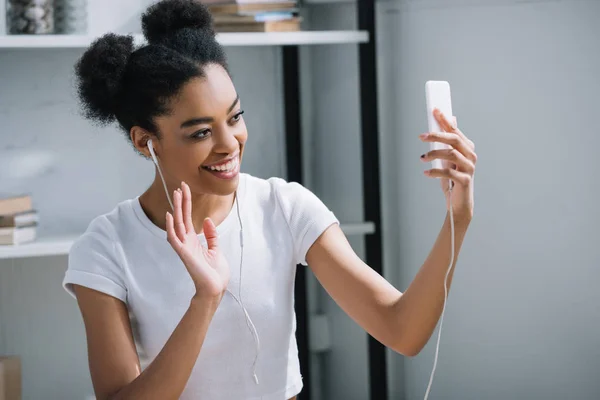 Счастливая молодая женщина совершает видеозвонок со смартфоном на дому — Stock Photo