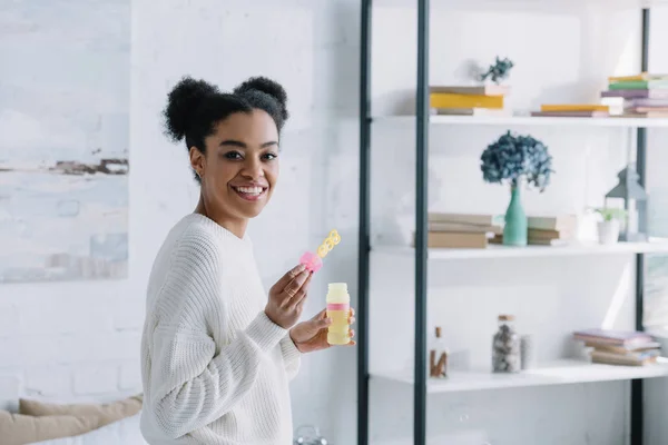 Vista lateral de la joven feliz con burbujas de jabón en casa - foto de stock
