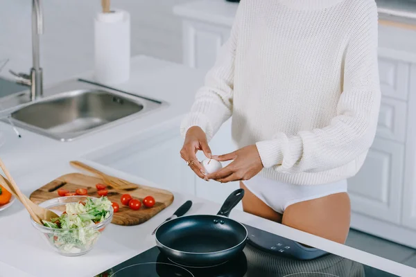 Schnappschuss einer Frau, die Eierschale bricht, um Rührei für das Frühstück in der Küche zuzubereiten — Stockfoto