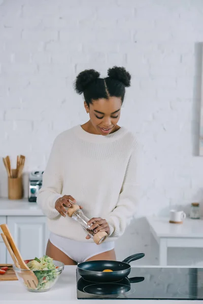 Hermosa mujer joven salpicando huevo revuelto en la sartén en la cocina — Stock Photo