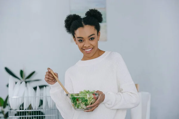 Feliz joven con tazón de ensalada saludable en la cocina - foto de stock