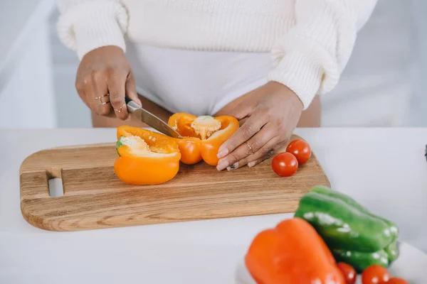 Colpo ritagliato di donna affettare il peperone per insalata a cucina — Foto stock