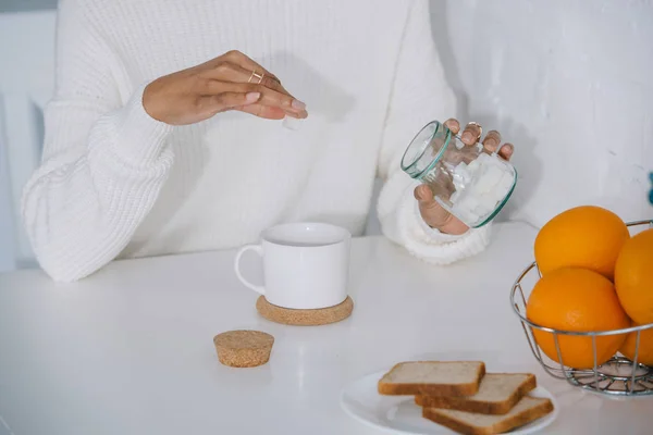 Recortado tiro de mujer añadiendo azúcar a su café en casa - foto de stock