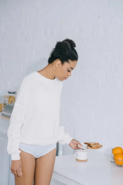 Schöne junge Frau mit Kaffeetasse und Toastteller zu Hause — Stockfoto