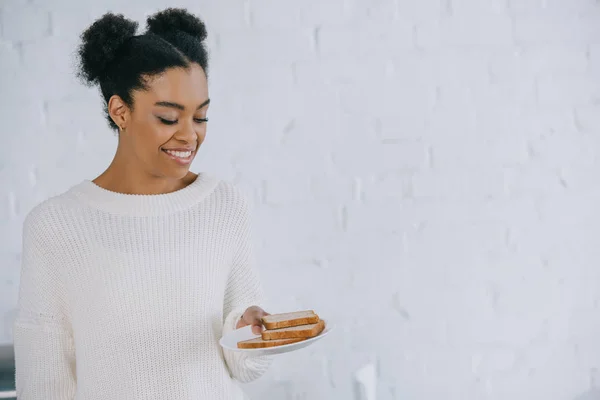 Красива молода жінка зі стопкою скибочок хліба на тарілці — стокове фото