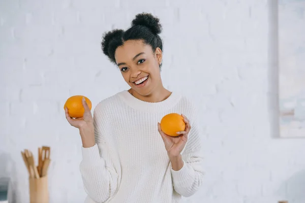 Feliz joven con naranjas frescas en la cocina - foto de stock