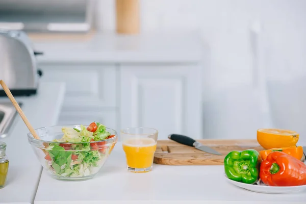 Close-up of fresh salad and orange juice on table at kitchen — Stock Photo
