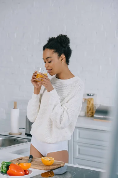 Beautiful young woman drinking fresh orange juice at home — Stock Photo