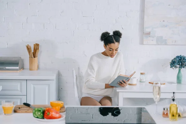 Bela jovem mulher ler livro na cozinha de manhã — Fotografia de Stock