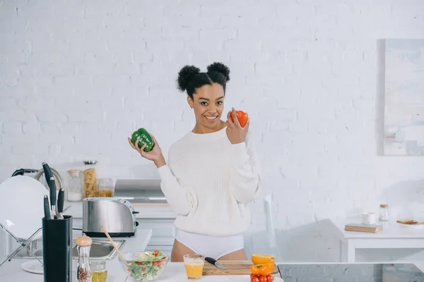 Beautiful young woman with ripe bell peppers at kitchen — Stock Photo