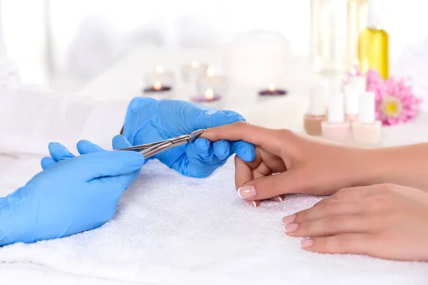 Imagen recortada de esteticista en guantes de látex haciendo manicura por cortauñas a la mujer en la mesa en el salón de belleza - foto de stock