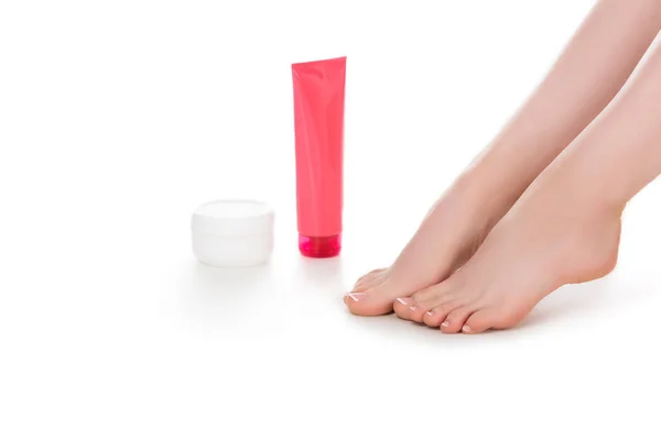Immagine ritagliata di donna scalza con contenitori crema per la cura della pelle isolata su sfondo bianco — Foto stock