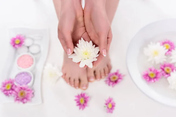 Partial view of barefoot woman holding flower on procedure in beauty salon — Stock Photo