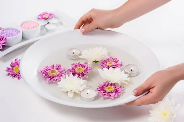 Colpo ritagliato di donna che tiene il bagno per unghie con fiori e candele aromatiche a tavola nel salone di bellezza — Foto stock