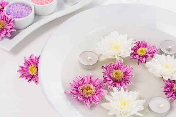 Закрытый вид на ванну для ногтей со свечами, цветами и красочной морской солью для маникюра и педикюра за столом в салоне красоты — стоковое фото