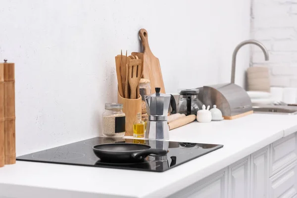 Sartén en el panel de inducción en la cocina moderna con varios utensilios — Stock Photo