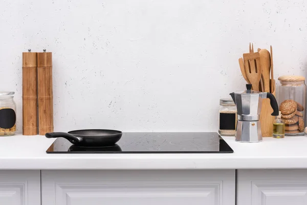 Frying pan on induction panel at modern kitchen in front of blank white wall — Stock Photo