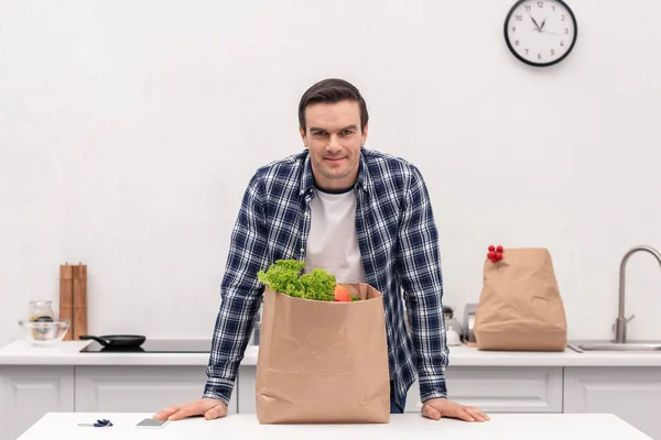 Schöner erwachsener Mann mit Lebensmittelgeschäft Papiertüte in der Küche — Stockfoto