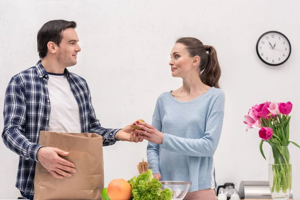 Feliz pareja adulta desembalaje bolsa de papel después de compras de comestibles - foto de stock