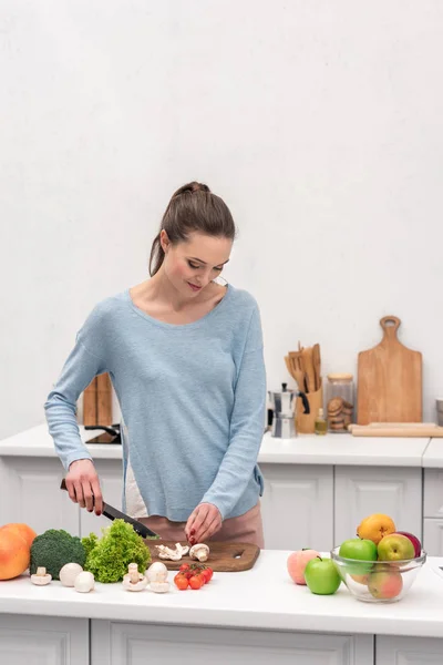 Beautiful adult woman cutting mushrooms at kitchen — Stock Photo