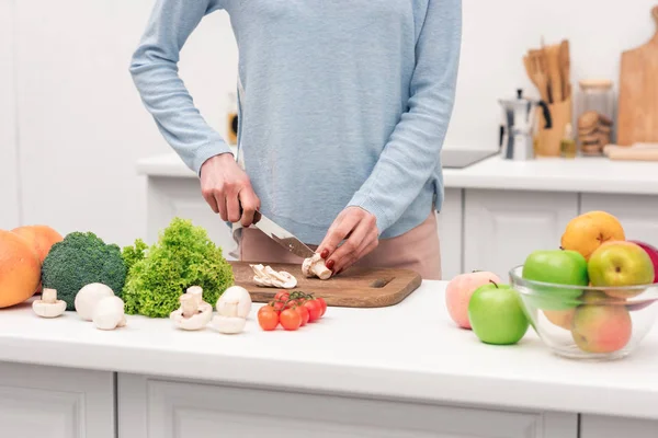 Cropped shot of woman cutting mushrooms at kitchen — Stock Photo