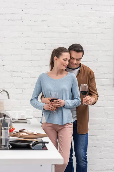 Beautiful adult couple with glasses of wine at kitchen — Stock Photo