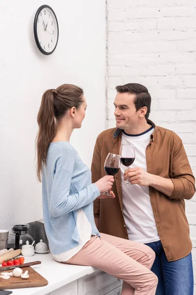 Hermosa pareja de adultos tintineo vasos de champán en la cocina - foto de stock