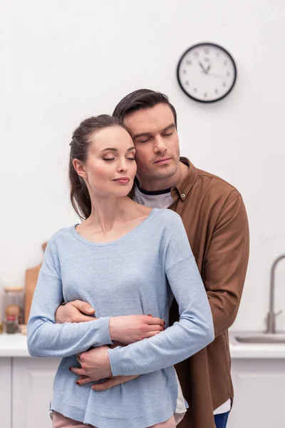 Feliz pareja adulta abrazando en la cocina - foto de stock