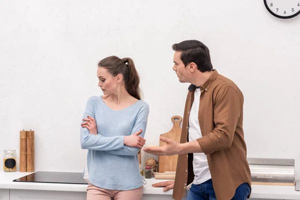 Mad adult man looking at wife while she ignoring him after argument at kitchen — Stock Photo