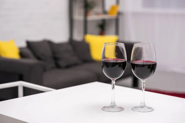 Close-up shot of red wine on table in front of blurred living room on background — Stock Photo