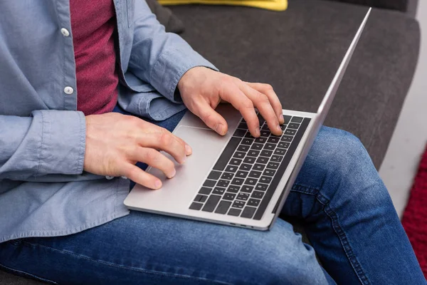 Обрезанный снимок человека, работающего с ноутбуком на диване — стоковое фото