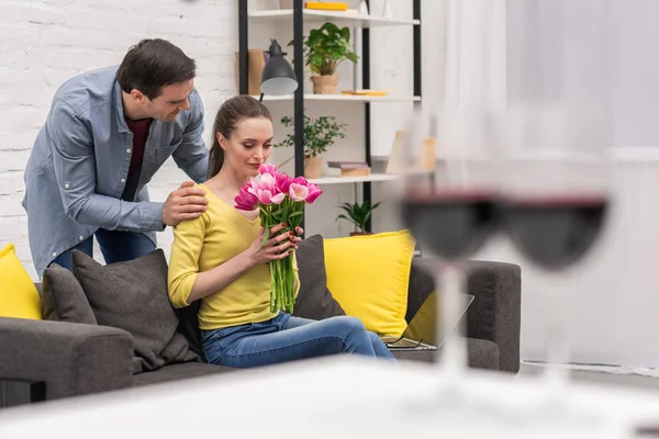 Schöner erwachsener Mann überreicht seiner Frau zu Hause einen Strauß Tulpen — Stockfoto