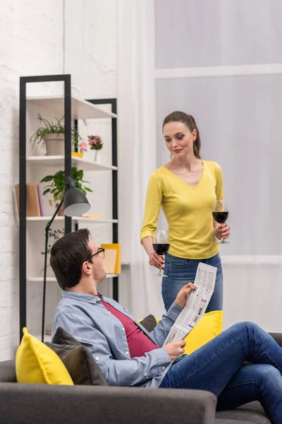Attractive adult woman giving glass of wine to her boyfriend at home — Stock Photo