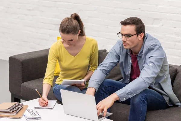 Fiduciosa coppia adulta di liberi professionisti che lavorano sul divano a casa insieme — Foto stock