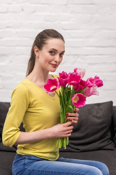 Attrayant adulte femme tenant bouquet de tulipes roses et regardant la caméra — Photo de stock