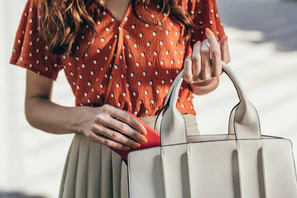 Обрезанный снимок женщины кладет смартфон в женскую сумку — стоковое фото