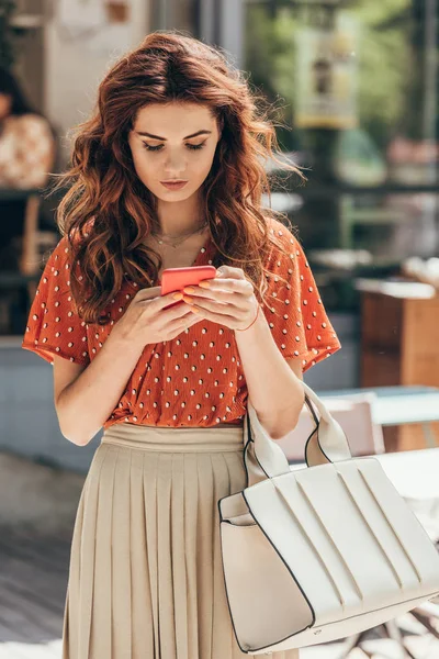 Portrait of young stylish woman using smartphone on street — Stock Photo