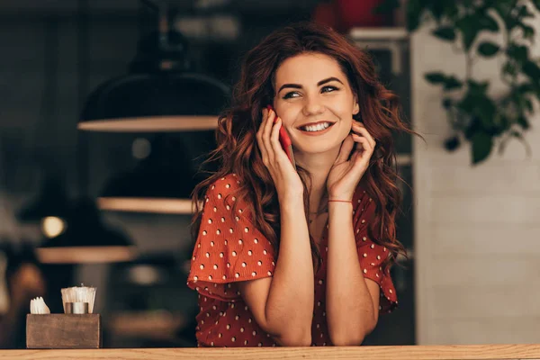 Портрет усміхненої жінки, що розмовляє на смартфоні в кафе — стокове фото