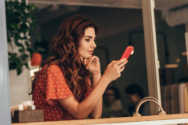 Боковой вид молодой женщины, использующей смартфон в кафе — стоковое фото