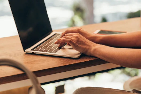 Vista parziale di blogger che digita su laptop con schermo bianco in caffetteria — Foto stock