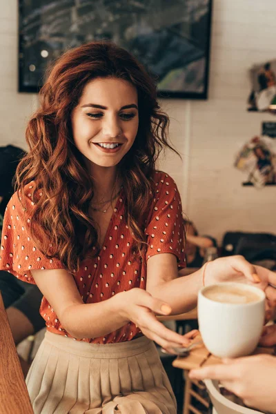 Partial view of woman taking cup of coffee from waitress in coffee shop — Stock Photo