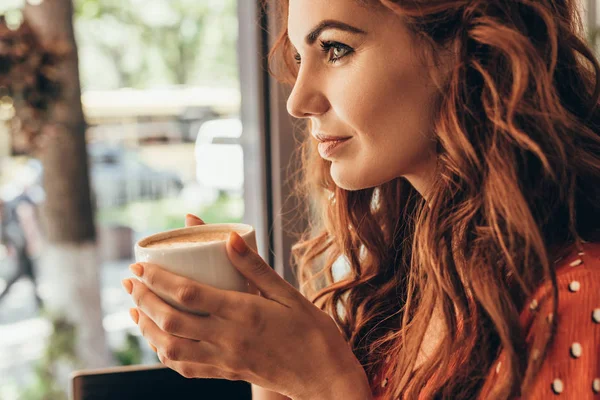 Vista lateral de la mujer pensativa con taza de café aromático en la cafetería - foto de stock