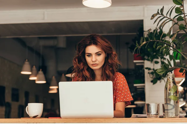 Porträt einer jungen Bloggerin, die in einem Café am Laptop arbeitet — Stockfoto