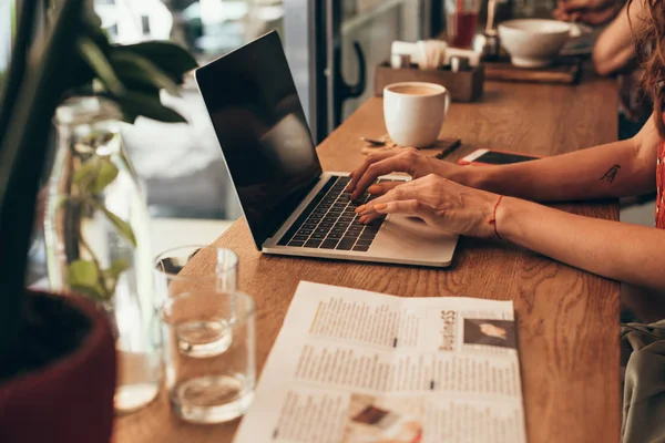 Cropped shot of blogger working on laptop with blank screen in coffee shop — Stock Photo