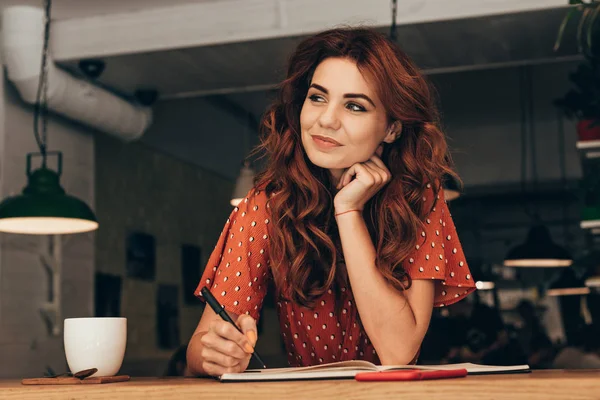 Porträt eines nachdenklichen Bloggers, der mit Notizbuch im Café am Tisch sitzt — Stockfoto